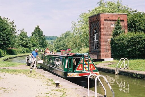 A traditional canal longboat by an old pump house